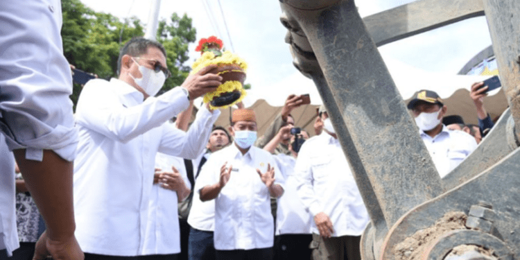 Pemecahan kendi di alat berat ekskavator oleh Pj Gubernur Gorontalo Hamka Hendra Noer saat mencanangkan pekerjaan kanal banjir Tanggidaa di Kecamatan Kota Timur, Kota Gorontalo, Rabu (18/5/2022). (Foto: Salman)