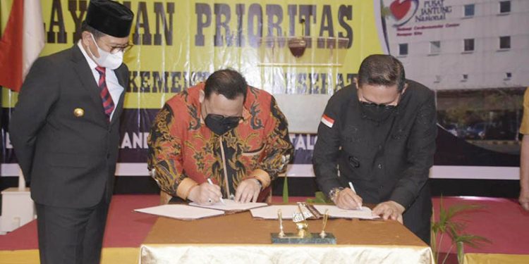 Wali Kota Gorontalo, Marten Taha (kanan) bersama Direktur Utama RSJPD Harapan Kita, Dr. Iwan Dakota (tengah) menandatangani MoU antara RSAS dan RSJPD Harapan Kita untuk pengembangan layanan penyakit jantung di RSAS Kota Gorontalo, Senin (27/6/2022). (Pemkot Gorontalo)