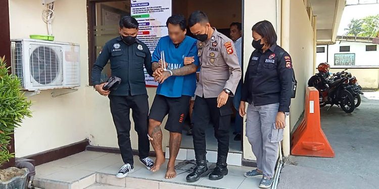 Tersangka pencurian sepeda motor, HW alias Gery dipapah personel Polres Gorontalo Kota. (Sari/gopos)