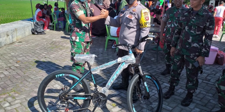 HUT Bhayangkara, Kapolres Bone Bolango, AKBP Emile Reisitei Hartanto saat menyerahkan hadiah utama satu unit sepeda kepada salah satu anggota TNI yang beruntung di HUT Bhayangkara ke-76, Jumat (17/6/2022). (Foto Indra/Gopos)