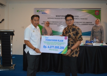 Kepala BPJamsostek Cabang Gorontalo, Hendra Elvian, menyerahkan pembayaran klaim kepesertaan, baik JKK dan JKM periode Januari 2022 – Juni 2022 sebesar Rp4,2 miliar lebih dengan 102 kasus kepada Bupati Bone Bolango Hamim Pou, pada kegiatan Monitoring dan Evaluasi Instruksi Presiden Nomor 2 Tahun 2021 di Hotel Toewawa, Kamis (23/6/2022). (Foto AKP/Diskominfo)