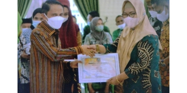 Bupati Gorontalo, Nelson Pomalingo saat memberikan penghargaan untuk salah satu Desa di Rapat Koordinasi Penetapan Hasil Pemutakhiran Data Indeks Desa Membangun (IDM) di Gedung Kasmat Lahay, Kabupaten Gorontalo, Selasa (5/7/2022). (Foto: Putra/Gopos)