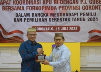 Ketua KPU RI, Hasyim Ashari (kiri) bersama Penjagub Gorontalo, Hamka Hendra Noer, bertukar cinderamata usai rapat koordinasi di aula rumah dinas Gubernur Gorontalo, Jumat (16/7/2022).(KPU Provinsi Gorontalo)
