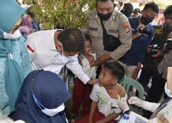 Pj Gubernur Gorontalo, Hamka Hendra Noer, menyemangati salah seorang siswa peserta imunisasi di Kejati Gorontalo, Selasa (19/7/2022). (Kominfo Provinsi Gorontalo)