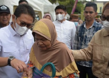 Penjagub Hamka Hendra Noer didampingi drg. Gamaria Monoarfa saat berbincang dengan salah satu masyarkat pembeli di pasar murah yang dilaksanakan di halaman Kantor Diskomperindag Provinsi Gorontalo, Jumat (8/7/2022). (Foto: Salman)