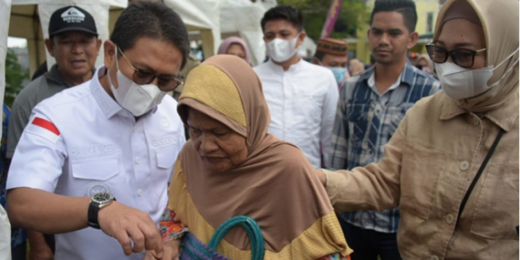 Penjagub Hamka Hendra Noer didampingi drg. Gamaria Monoarfa saat berbincang dengan salah satu masyarkat pembeli di pasar murah yang dilaksanakan di halaman Kantor Diskomperindag Provinsi Gorontalo, Jumat (8/7/2022). (Foto: Salman)