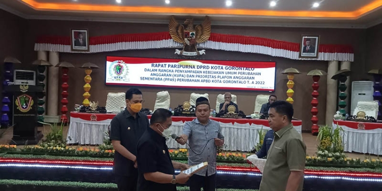 Wali Kota Gorontalo, Marten Taha menyerahkan perubahan anggaran dan prioritas plafon anggaran sementara, anggaran pendapatan belanja daerah Kota Gorontalo, tahun anggaran 2022, kepada Ketua DPRD Kota Gorontalo, Hardi Sidiki. Jum'at (12/8/2022). Foto : Sari/gopos