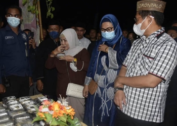 Penjabat Gubernur Hamka Noer didampingi istri drg. Gamari Monoarfa juga anggota DPR RI Komisi VIII Idah Syahidah saat meninjau stand masyarakat yang menyajikan kue apangi secara gratis pada Festival Apangi oleh masyarakat Kecamatan Tibawa, Senin (8/8/2022). Foto Salman