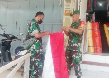 Babinsa, Kodim 1304 Gorontalo, saat menghampiri pelaku usaha untuk memasang bendera merah putih. Foto : istimewa.