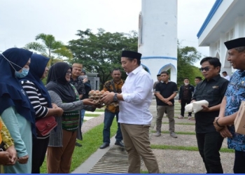 Bupati Hamim Pou menyerahkan secara simbolis bantuan stabilitasi pasokan dan harga pangan tahun 2022, kepada perwakilan pedagang kios di wilayah Kecamatan Kabila dan Tilongkabila, di halaman Masjid Agung Baitul Haq Islamic Center Bone Bolango, Jumat (15/7/2022). (Foto AKP/Diskominfo)