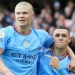 Penyerang Manchester City, Erling Haaland (kiri) dan gelandang serang Phil Foden merayakan gol ke gawang Manchester United pada laga Liga Inggris di Stadion Etihad, Manchester, Minggu (2/10/2022) malam WIB. [AFP/Suara.com]