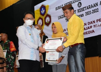 Penjagub Hamka Hendra Noer saat menyerahkan ijazah kepada perwakilan warga putus sekolah yang berhasil menyelesaikan belajar mengajar pada Pusat Kegiatan Belajar Mengajar (PKBM) Sweet Media berupa ijazah paket a b c, Sabtu (15/10/2022). (Kominfo Gorontalo)