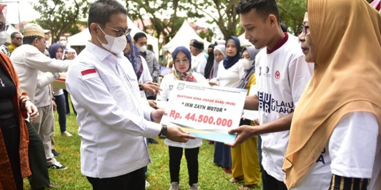 Penjagub Hamka Hendra Noer saat menyerahkan secara simbolis bantuan kepana pelaku IKM Provinsi Gorontalo, melalui kegiatan Temu Akbar Pelaku Usaha yang digelar di halaman kantor Dinas Koperasi, UMKM, Perindustrian dan Perdagangan (Diskumperindag), Jumat (18/11/2022). (Dinas Kominfo Provinsi Gorontalo)