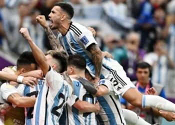 Gelandang Argentina Leandro Paredes melompati rekan satu timnya saat mereka selebrasi ketika pemain depan Argentina Lionel Messi mencetak gol saat pertandingan sepak bola perempat final Piala Dunia 2022 antara Belanda dan Argentina di Stadion Lusail, utara Doha, Qatar, Jumat (9/12/2022). [MANAN VATSYAYANA/AFP]