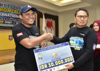 Penjagub Hamka saat menyerahkan uang tunai secara simbolis kepada pemenang lomba Gorontalo Underwater Photography Competition seri-1 tahun 2022, kategori camera compact yang diraih oleh peserta asal Manado. (Foto – Fikri)