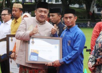 Ketua DPRD Bone Bolango, Halid Tangahu saat menyerahkan penghargaan kepada salah satu penerima penghargaan di Bone Bolango. (Foto : Humas)