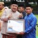 Ketua DPRD Bone Bolango, Halid Tangahu saat menyerahkan penghargaan kepada salah satu penerima penghargaan di Bone Bolango. (Foto : Humas)