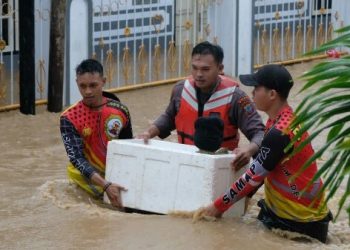 Personel Samapta Polda Sulut mengekuasi balita yang terjebak banjir di Kelurahan Ternate Tanjung, Kecamatan Singkil, Manado, Jumat (27/1/2023). (Dok. Polda Sulut)