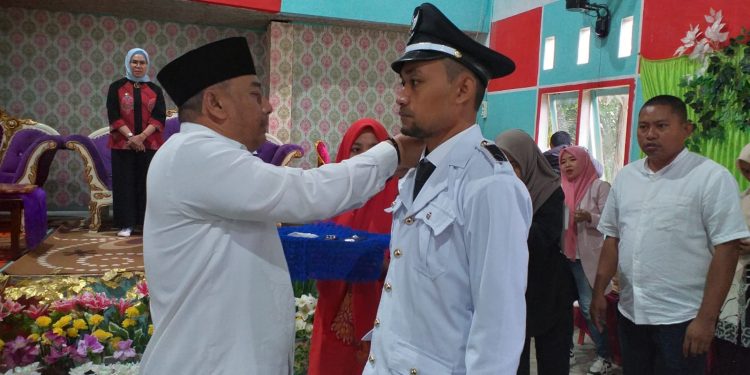 : Bupati Bone Bolango, Hamim Pou saat memasang tanda jabatan kepada Kepala Desa Poduwoma, Agus Salim Ishak, Sabtu (21/1/2023). (Foto Indra/Gopos)