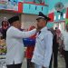 : Bupati Bone Bolango, Hamim Pou saat memasang tanda jabatan kepada Kepala Desa Poduwoma, Agus Salim Ishak, Sabtu (21/1/2023). (Foto Indra/Gopos)