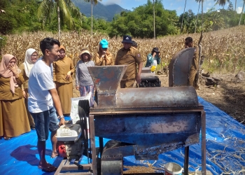 Efendi Lahay saat mempraktekkan cara kerja mesin pengupas dan pemipil jagung dihadapan Wakil Bupati Bone Bolango, Merlan S. Uloli dan Kepala Dinas Ketahanan Pangan dan Pertanian Yusbar Ismail, Senin (2/1/2023). (Foto Indra/Gopos)