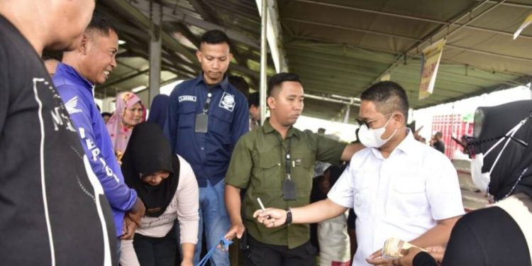 Penjagub Hamka saat melayani masyarakat di pasar murah yang digelar pemprov Gorontalo untuk warga Telaga Jaya, Desa Buhu, Minggu, (25/12/2022). Foto – Nova