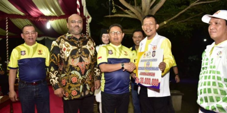 Penjagub Hamka Hendra Noer saat menyerahkan secara simbolis bonus uang tunai kepada juara umum dalam hal ini Kota Gorontalo yang meraih banyak medali pada ajang Pekan Olahraga Provinsi (Porprov) Gorontalo tahun 2022, Jumat malam (23/12/2022), di lapangan Tarun Remaja Kota Gorontalo. (Foto – Fikry)