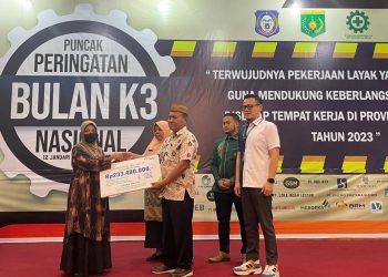 Staf Ahli Gubernur Gorontalo, Yosep P. Koton didampingi Kepala BPJS Ketenagakerjaan Cabang Gorontalo, Arif Budiman saat menyerahkan santunan kecelakaan kerja kepada salah satu ahli waris pada Puncak Peringatan Bulan K3 Nasional tingkat Provinsi Gorontalo di Hotel Dumhil, Jumat (10/2/2023). (Foto Istimewa)