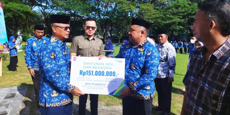 Sekda Bone Bolango, Ishak Ntoma yang turut didampingi Kepala BPJS Ketenagakerjaan Cabang Gorontalo, Arif Budiman saat menyerahkan santunan kepada ahli waris anggota Korpri, Jumat (17/2/2023). (Foto AKP/Diskominfo)