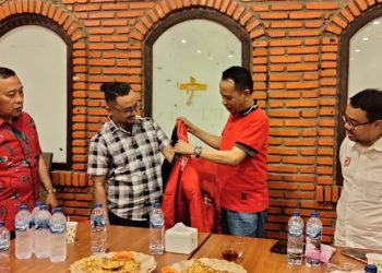 Ketua Dewan Pimpianan Wilayah Partai Berkarya Gorontalo Fadryanto Nusa saat dipakaikan Jaket sebagai Atribut Partai Solidaritas Indonesia (PSI) oleh Ketua Dewan Pertimbangan PSI Badarudin Andi Picunang, di Rumah Makan Mawar Saron Kota Gorontalo, Rabu (05/4/2023). (foto.istimewa)