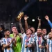 Gelandang Argentina Enzo Fernandez mengangkat Trofi Piala Dunia dan memegang penghargaan Pemain Muda selama upacara Trofi saat ia merayakan dengan rekan setimnya memenangkan pertandingan sepak bola final Piala Dunia 2022 antara Argentina dan Prancis di Stadion Lusail di Lusail, utara Doha, Qatar, Minggu (18/12/2022). [Kirill KUDRYAVTSEV / AFP]