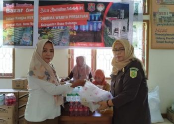 Ketua DWP Bone Bolango, Mariyani Ntoma Liputo saat menyerahkan paket sembako yang dibeli oleh salah seorang tenaga honorer pada pelaksanaan bazar, Senin (17/4/2023). (Foto AKP/Diskominfo)
