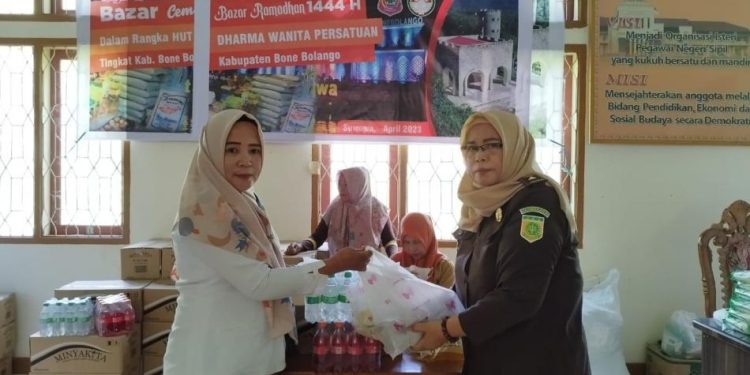 Ketua DWP Bone Bolango, Mariyani Ntoma Liputo saat menyerahkan paket sembako yang dibeli oleh salah seorang tenaga honorer pada pelaksanaan bazar, Senin (17/4/2023). (Foto AKP/Diskominfo)
