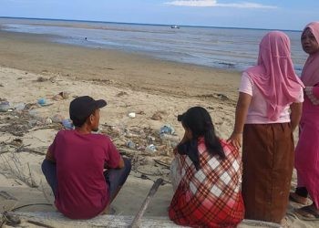 Orang tua RK menunggu di muara sungai Marisa usai putranya RK hilang tenggelam di muara sungai Marisa.(yusuf/gopos)