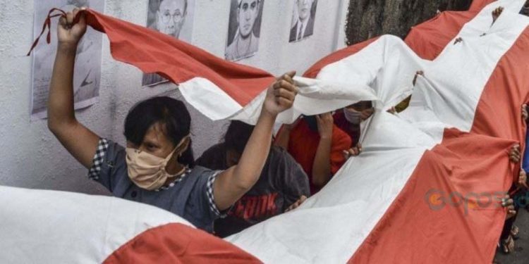 Beberapa orang memegang bendera nasional Indonesia saat mengikuti tradisi cuci bendera merah putih di Jenggala, Ciamis, Jawa Barat, Jumat (14 Agustus 2020). (ANTARA PHOTO/Adeng Bustomi/aww)