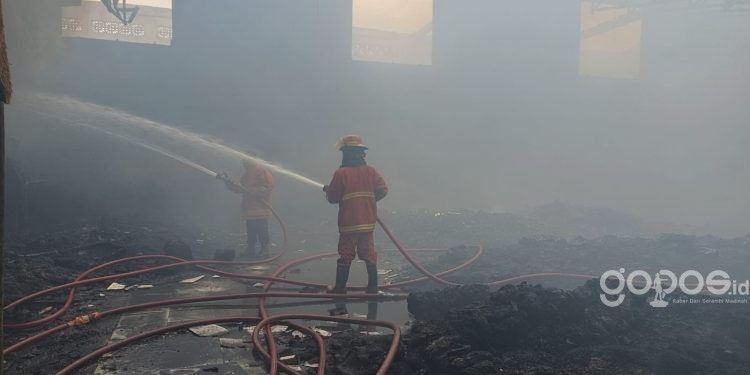 Salah satu petugas Damkar masih terus berupaya memadamkan titik-titik api di gudang sepatu milik toko Utama Shoes Kota Gorontalo, Jumat (16/6/2023). (putra/istimewa)