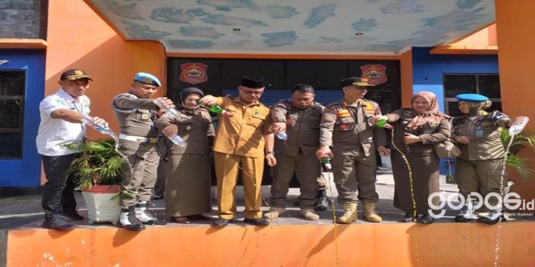 Sekda Bone Bolango, Ishak Ntoma didampingi Plt Kepala Satpol PP Bone Bolango, Fredy Lasut saat memusnahkan barang bukti miras hasil sitaan operasi, Selasa (13/6/2023). (Foto Indra/Gopos)