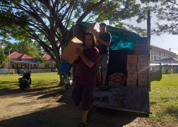 Anggota Satuan Reserse Narkoba Polres Bone Bolango saat menurunkan barang bukti miras jenis cap tikus dari truk, Minggu (6/8/2023). (Foto Indra/Gopos)