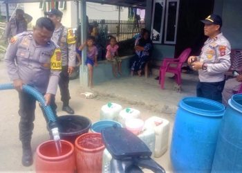 Jajaran Polsek Paguyaman Pantai saat mendistribusikan air bersih untuk warga.(f.tribrata)