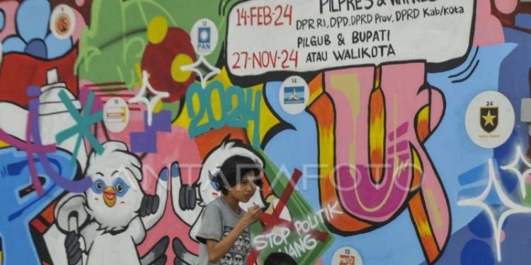 Dua anak berjalan melintasi mural Pemilu 2024 di Pandeglang, Banten, Senin (6/3/2023). Mural tersebut bertujuan untuk mengajak warga berpartisipasi dalam menyukseskan Pemilu 2024 serta menolak politik uang. (ANTARA FOTO/Muhammad Bagus Khoirunas/rwa.)