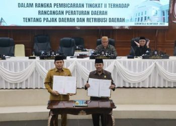 Pj Gubernur Gorontalo, Ismail Pakaya dan Ketua DPRD Provinsi Gorontalo, Paris RA Jusuf menandatangani kesepakatan pengesahan ranperda pajak dan retribusi daerah melalui rapat paripurna dewan, Senin (16/9/2023) (istimewa)