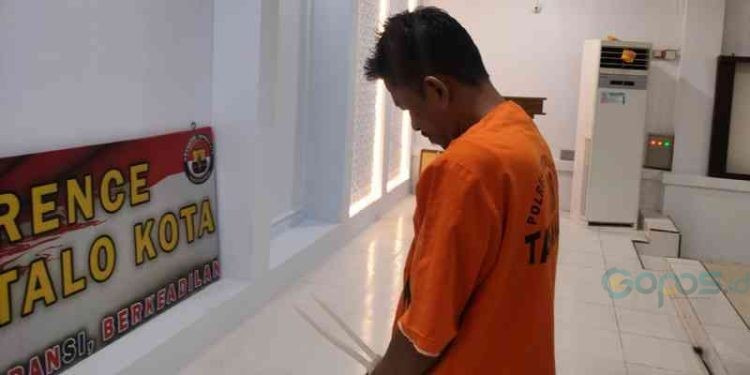 Tersangka ADE tertunduk lesu pada saat konferensi pers di Polresta Gorontalo Kota, Selasa (17/10/2023). (F. Putra/gopos)