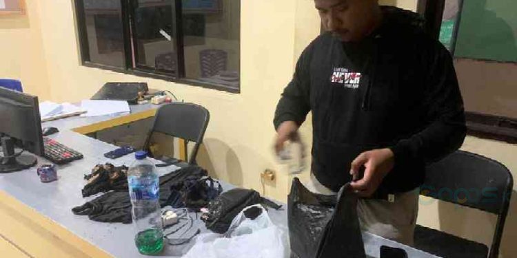 Pihak kepolisian saat mengamankan sejumlah barang bukti korban.