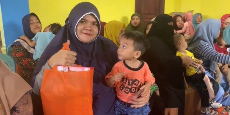 Indy Anggraini warga Kecamatan Bulango Timur saat tersenyum bahagia usai menerima bantuan intervensi stunting dari Pemerintah Kabupaten Bone Bolango. Rabu (15/11/2023). (Foto Adit)