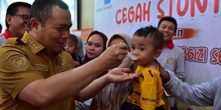 Penjabat Gubernur Gorontalo Ismail Pakaya memberikan makanan tambahan kepada salah satu anak bertempat di Aula Balai Guru Penggerak, Kecamatan Telaga Biru, Kabupaten Gorontalo, Senin (13/11/2023). (F. Isam/humasprov)