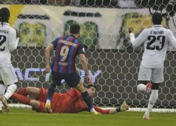 Penyerang Barcelona, Robert Lewandowski saat mencetak gol ke gawang Real Madrid pada final Piala Super Spanyol di Stadion King Fahd, di Riyadh, Arab Saudi, Senin (16/1/2023). Di pertandingan ini Lewandowski juga memberikan assist kepada Gavi yang mencetak gol. (AP Photo/Hussein Malla)