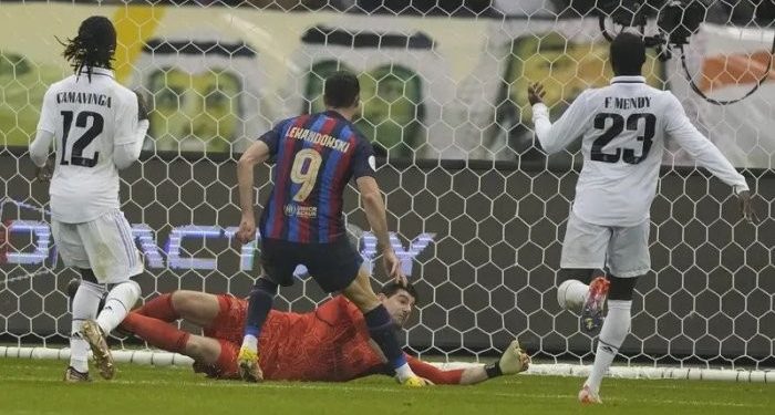 Penyerang Barcelona, Robert Lewandowski saat mencetak gol ke gawang Real Madrid pada final Piala Super Spanyol di Stadion King Fahd, di Riyadh, Arab Saudi, Senin (16/1/2023). Di pertandingan ini Lewandowski juga memberikan assist kepada Gavi yang mencetak gol. (AP Photo/Hussein Malla)