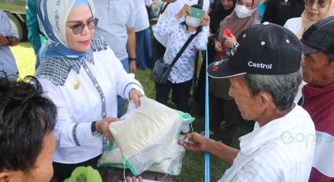 Bupati Merlan S. Uloli saat menyerahkan bahan pokok beras kepada warga pada pelaksanaan pasar murah di wilayah Suwawa Cs, Rabu (7/2/2024). (Foto Yudi/Sespri)
