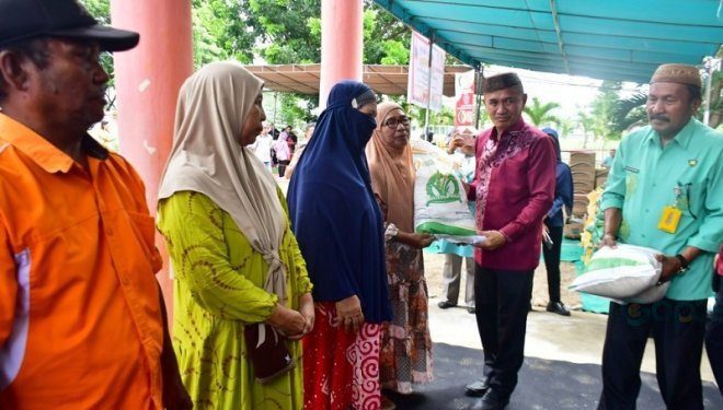 Bupati Pohuwato, Saipul Mbuinga Memberikan Bantuan Beras Gratis Secara Simbolis Kepada Salah Satu KPM, berlangsung di halaman dinas pangan Pohuwato, Kamis (1/2/2024). (F Humas Pemda Pohuwato)