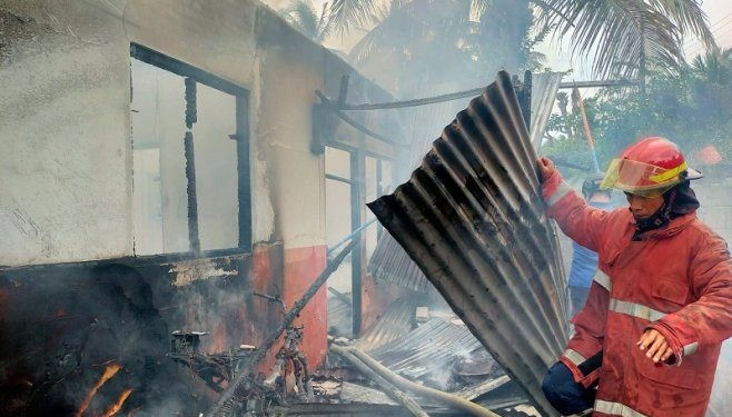 Seorang petugas Damkar saat berusaha memadamkan sisa-sisa api yang membakar sebuah rumah di Desa Ulapato, Kecamatan Telaga Biru, Kabupaten Gorontalo, Jumat (2/2/2024).